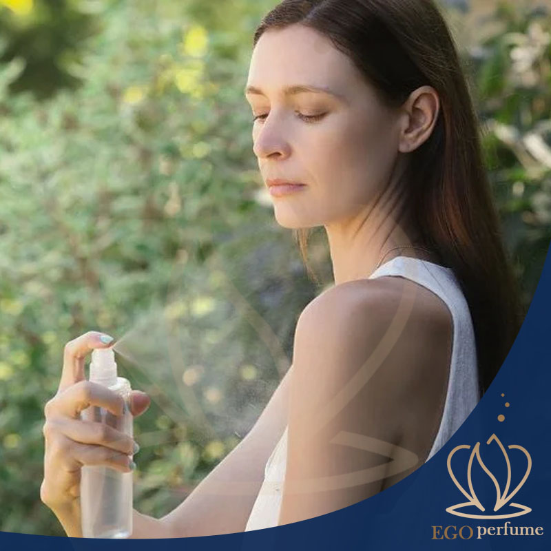 تفاوت بادی‌اسپلش و عطر؛ هرآنچه باید بدانید. یک خانوم در حال اسپری کردن بادی اسپلش